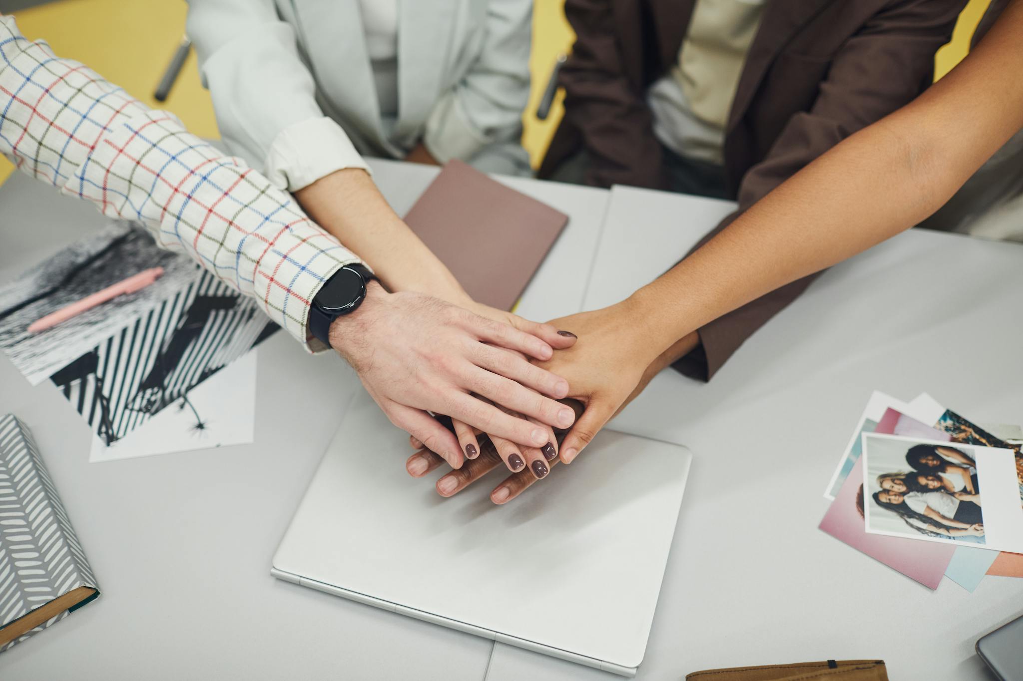 Close-up of diverse business team joining hands over a laptop, symbolizing teamwork and unity.